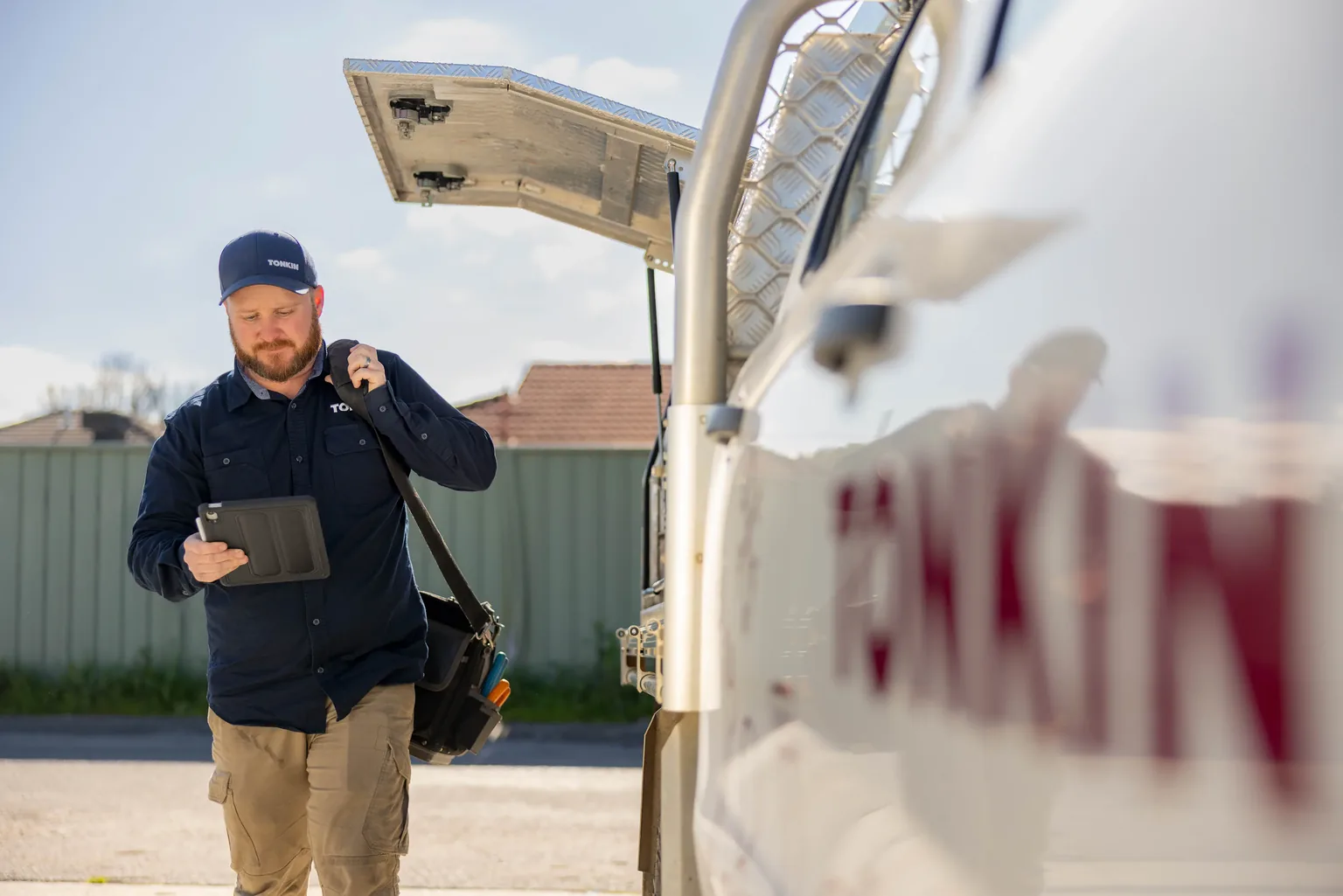 A Tonkin technician using an iPad beside a service vehicle